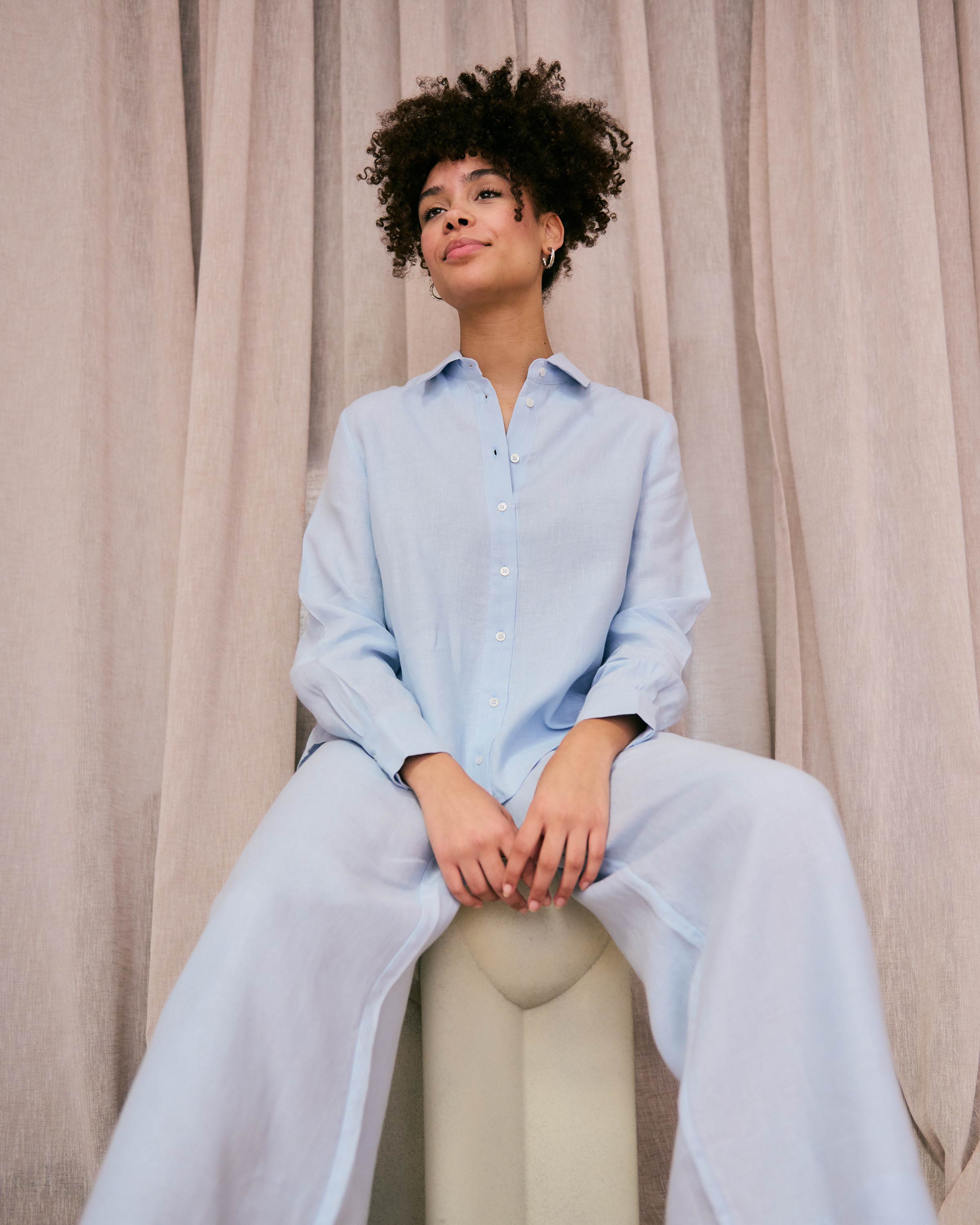 Sitting woman wearing comfortable light blue linen trousers and blouse by mana loa.