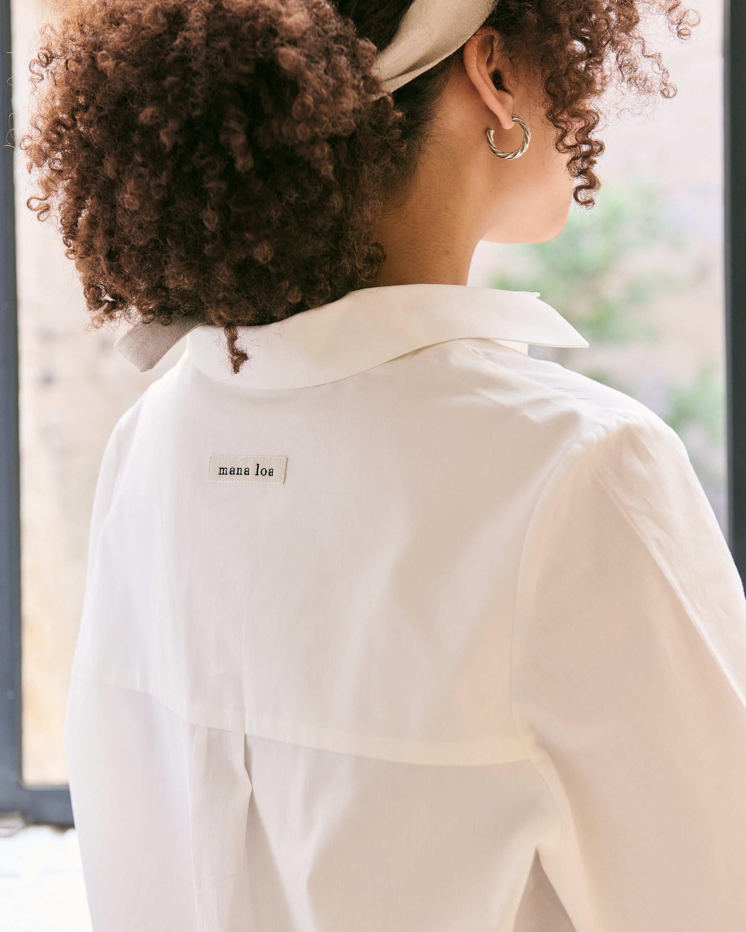 Detal of the back of an offwhite cotton shirt with mana loa label.