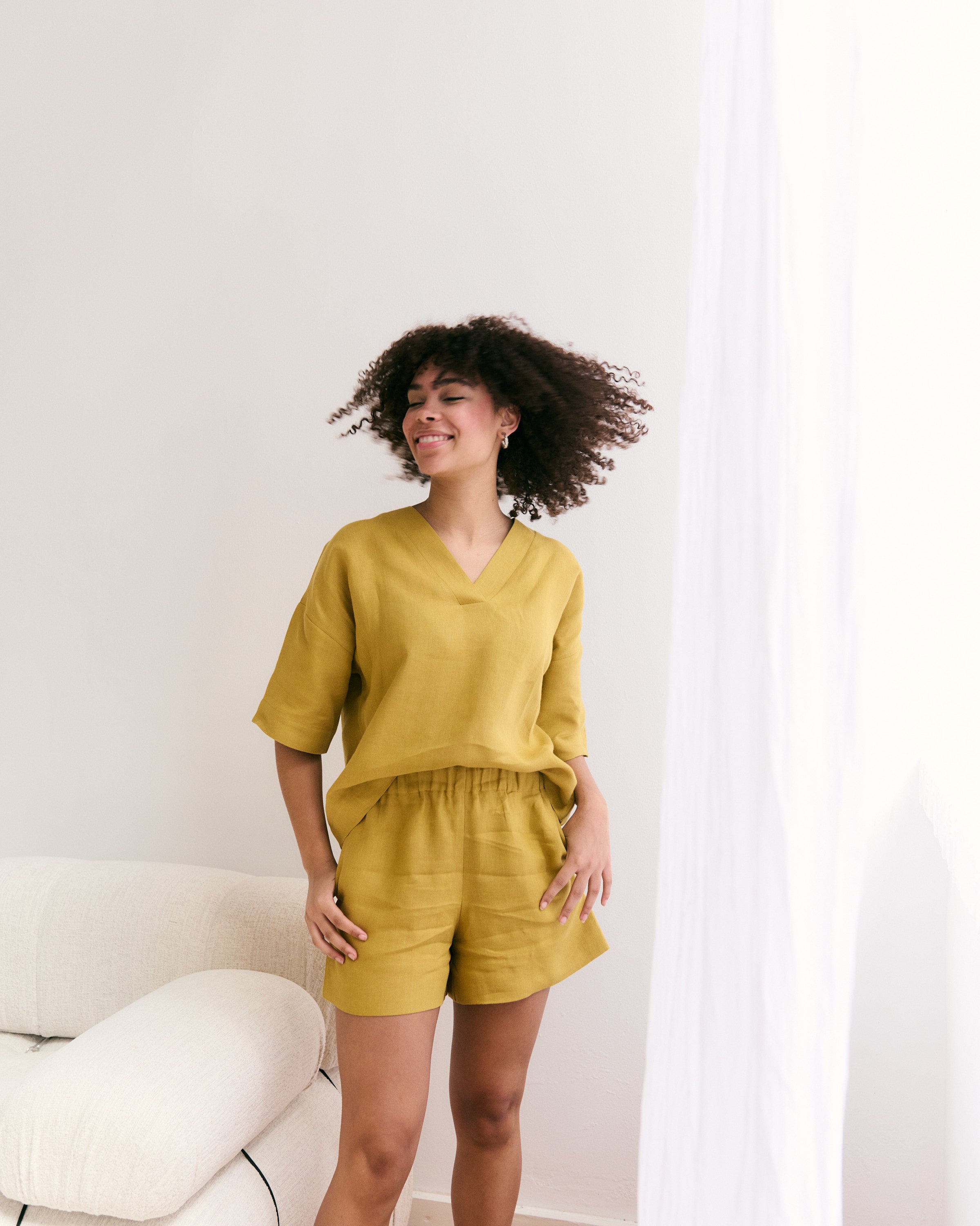 Happy girl in mana loa linen shorts and blouse in mustard colour.