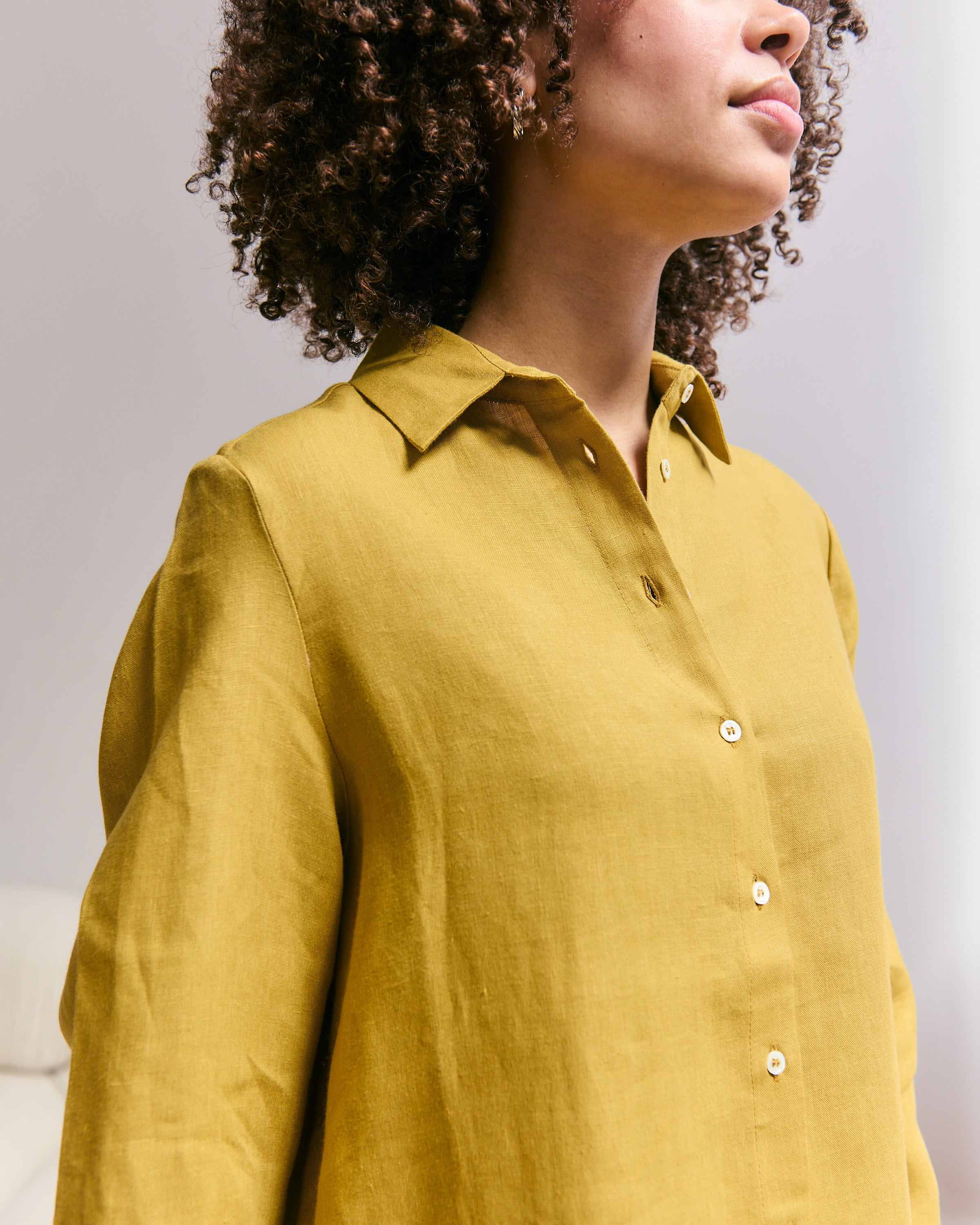 Detail of a comfortable and light mustard jellow Belgian linen shirtdress.